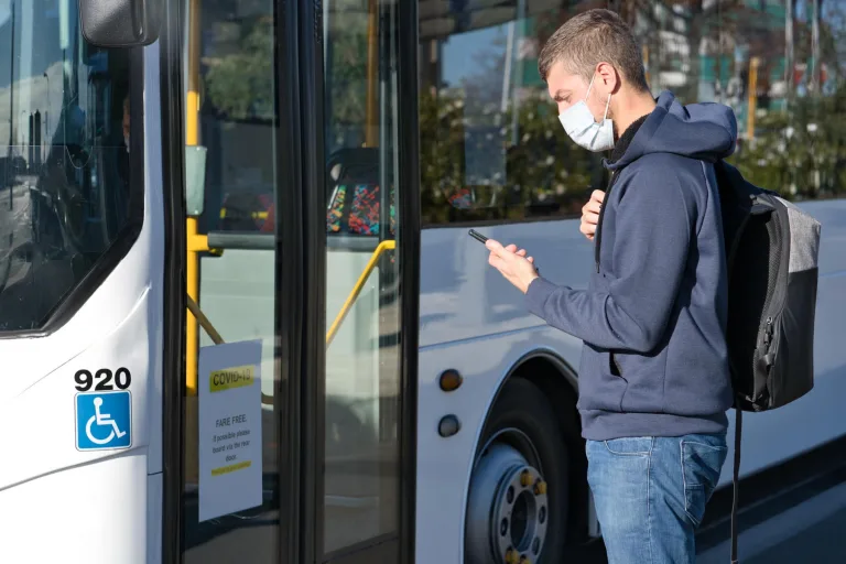 A man wearing a face mask looking at his phone